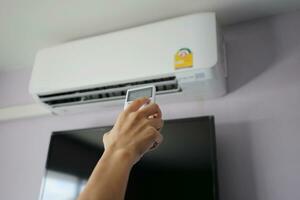 afstandsbediening in de hand gericht op de airconditioner foto