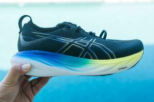 Bangkok, Thailand - januari 7, 2024 Mens hand- Holding een schoen van asics rennen schoenen gel nimbus 25 breed. foto