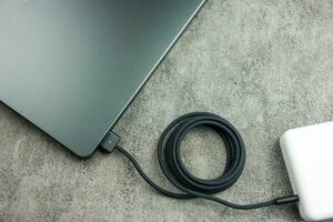 Bangkok, Thailand - december 28, 2023 een zwart gevlochten usb-c kabel in rekening brengen en aansluiten naar appel MacBook pro met m3 max. hoogte foto