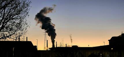 de smog van fabriek schoorstenen met de kleuren van de zonsondergang in Italië foto