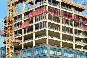 hoog stijgen gebouw onder bouw. installatie van glas facade panelen Aan een versterkt beton structuur. foto