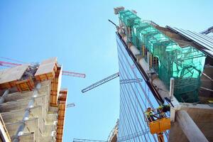hoog stijgen gebouw onder bouw. installatie van glas facade panelen Aan een versterkt beton structuur. foto