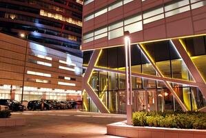 fragment van de glas facade van een modern zakelijke gebouw Bij nacht. modern glas kantoor in stad. groot gloeiend ramen in modern kantoor gebouwen Bij nacht, in rijen van ramen licht schijnt. foto