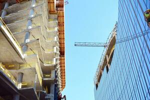 hoog stijgen gebouw onder bouw. installatie van glas facade panelen Aan een versterkt beton structuur. foto