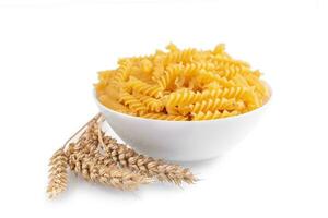 rauw pasta fusilli in kom en tarwe aartjes geïsoleerd Aan wit achtergrond foto