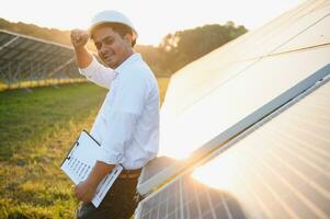 een Indisch mannetje ingenieur werken Aan een veld- van zonne- panelen. de concept van hernieuwbaar energie foto