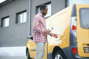 Afrikaanse Amerikaans Mens opladen zijn elektrisch auto. foto