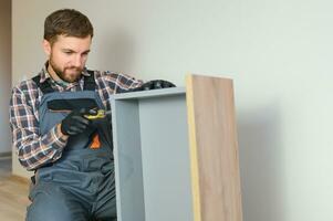 professioneel meubilair bijeenkomst arbeider assembleert plank. professioneel klusjesman aan het doen bijeenkomst baan goed foto