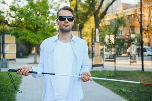 jong knap verblind Mens wandelen met stok in stad- foto