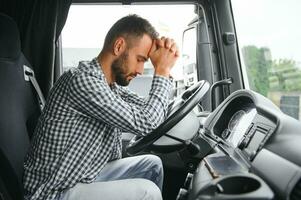 Mens vrachtwagenchauffeur moe het rijden in een cabine van zijn vrachtauto foto