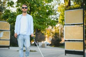 jong knap verblind Mens wandelen met stok in stad- foto