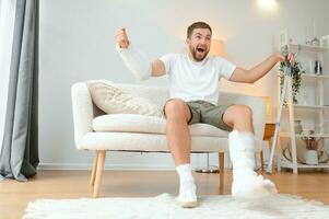 Mens met meerdere fysiek ledemaat en lichaam verwondingen herstelt na ongeluk. gelukkig vent hebben pret Bij huis foto