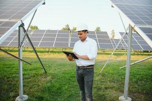 portret van een jong Indisch mannetje ingenieur of architect Bij een zonne- paneel boerderij. de concept van schoon energie foto