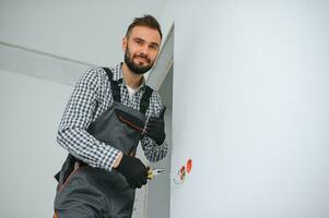 echt mannetje elektricien installeren macht stopcontact in de appartement en gebruik makend van schroevedraaier foto