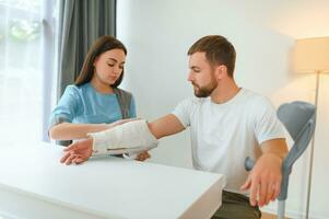 mooi jong dokter zetten een verband Aan een mannetje patiënten arm na schoonmaak een wond in een ziekenhuis foto