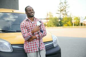 Afrikaanse Amerikaans Mens opladen zijn elektrisch auto. foto