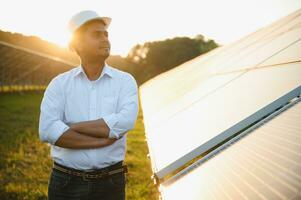 een Indisch mannetje ingenieur werken Aan een veld- van zonne- panelen. de concept van hernieuwbaar energie foto