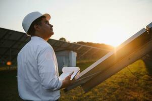 een Indisch mannetje ingenieur werken Aan een veld- van zonne- panelen. de concept van hernieuwbaar energie foto