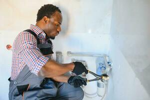 Afrikaanse Amerikaans loodgieter installeert of verandering water filter. vervanging aqua filter foto