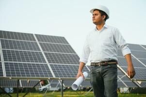 een Indisch mannetje ingenieur werken Aan een veld- van zonne- panelen. de concept van hernieuwbaar energie foto