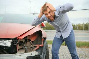 een gefrustreerd Mens in de buurt een gebroken auto. gepakt mijn hoofd realiseren de schade is echt, de auto is verder reparatie foto