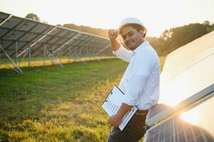 portret van een jong Indisch mannetje ingenieur of architect Bij een zonne- paneel boerderij. de concept van schoon energie foto