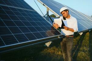 een Indisch mannetje ingenieur werken Aan een veld- van zonne- panelen. de concept van hernieuwbaar energie foto