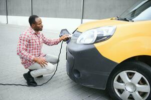 Afrikaanse Amerikaans Mens opladen auto Bij voertuig opladen station foto