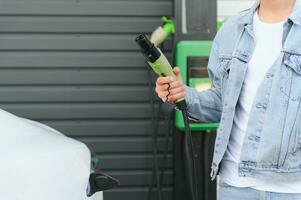 Mens Holding macht levering kabel Bij elektrisch voertuig opladen station. detailopname foto