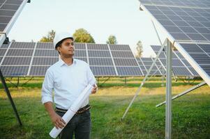 portret van een jong Indisch mannetje ingenieur of architect Bij een zonne- paneel boerderij. de concept van schoon energie foto