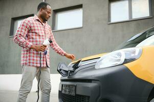 Afrikaanse Amerikaans Mens opladen zijn elektrisch auto. foto