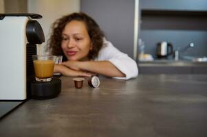 details Aan een transparant glas kop met vers gebrouwen espresso koffie met schuim Aan capsule koffie machine voor huis gebruiken. foto