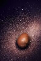 gouden ei en verf verstuiven heelal Aan Purper achtergrond. abstract kosmos. gelukkig Pasen concept foto