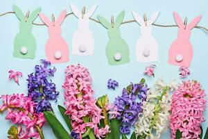 gelukkig Pasen groet kaart. veelkleurig hyacint bloemen en papier konijntjes guirlande. Pasen concept. vlak leggen foto