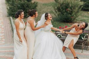 bruiloft foto in natuur. een brunette bruid in een wit lang jurk en haar vrienden in naakt jurken zijn voor de gek houden in de omgeving van samen en glimlachen oprecht. jong Dames. emoties