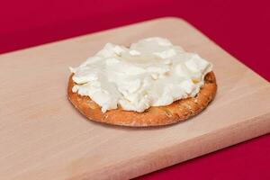 krokant kraker belegd broodje met room kaas Aan houten Koken bord Aan magenta achtergrond foto