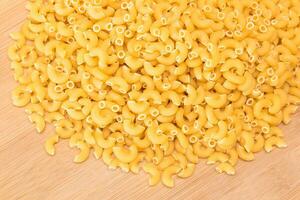 een hoop van ongekookt chifferi rigati pasta Aan houten keuken bord. dik en ongezond voedsel. klassiek droog macaroni. Italiaans cultuur en keuken. rauw pasta foto