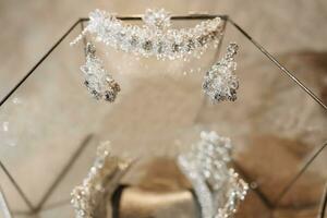 bruiloft kroon tiara in een glas doos Aan de bed, armband Aan de hand- van de bruid en Koninklijk oorbellen. luxe accessoires foto