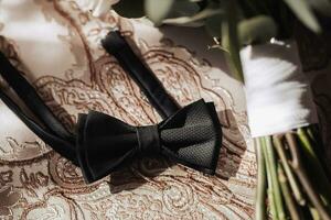 Mannen accessoires. zwart zijde boog stropdas Aan een mooi goud tafelkleed. licht en schaduwen. bruiloft details. Mannen stijl foto