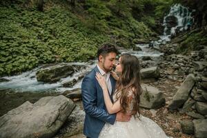 portret van een gelukkig bruid en bruidegom in de buurt een waterval. bruid en bruidegom. bruiloft foto sessie in natuur. foto sessie in de Woud van de bruid en bruidegom.