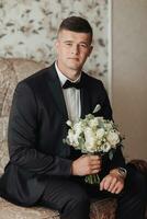 portret. een Mens in een wit shirt, een zwart boog stropdas en een zwart pak poses in een kamer met een bruiloft boeket. een elegant horloge. Mannen stijl. mode. bedrijf foto