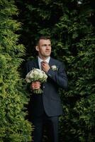 een Mens in een zwart pak poses in natuur met een boeket. een elegant horloge. Mannen stijl. mode. bedrijf. foto