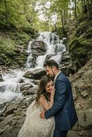 portret van een gelukkig bruid en bruidegom in de buurt een waterval. bruid en bruidegom. bruiloft foto sessie in natuur. foto sessie in de Woud van de bruid en bruidegom.