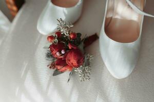 details van de bruid Aan een zacht roze stoel, de bruiloft corsages en de bruid schoenen zijn wit foto