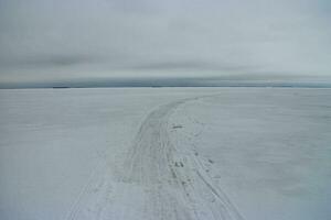 winter weg Aan de ijs van een breed bevroren rivier- gaat verder de horizon, winter landschap foto