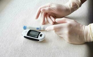 dichtbij omhoog schot van de glucometer instrument Aan de wit oppervlak. verpleegster helpen geduldig naar controleren suiker niveau. gezondheidszorg foto