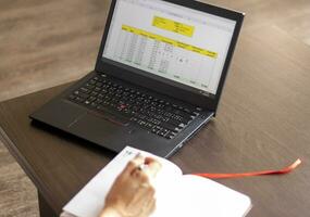 schot van een vrouw werken Aan de laptop tonen een excelleren vel Aan de scherm met bank lening afschrijvingen tafel. accounting foto