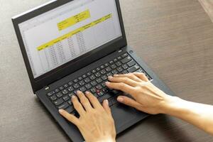 schot van een vrouw werken Aan de laptop tonen een excelleren vel Aan de scherm met bank lening afschrijvingen tafel. accounting foto