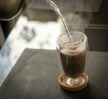 schot van de heet water wezen gegoten in de transparant kop naar brouwen de koffie. drank foto
