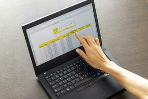 schot van een vrouw werken Aan de laptop tonen een excelleren vel Aan de scherm met bank lening afschrijvingen tafel. accounting foto